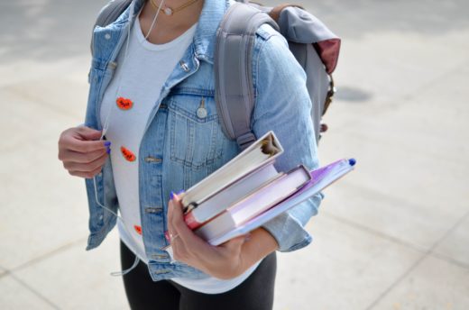 Student holding books with a backpack on